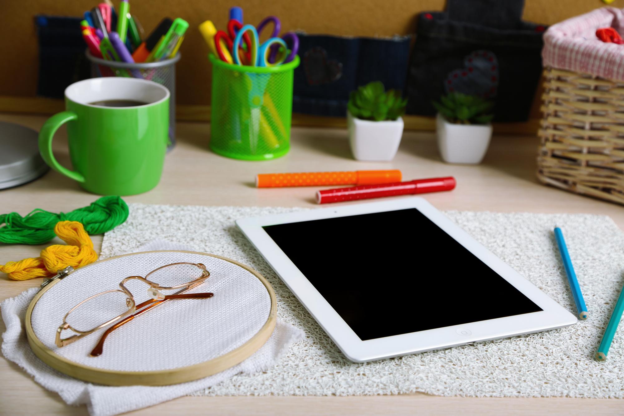 Student workspace with hoop, threads and tablet showing lesson